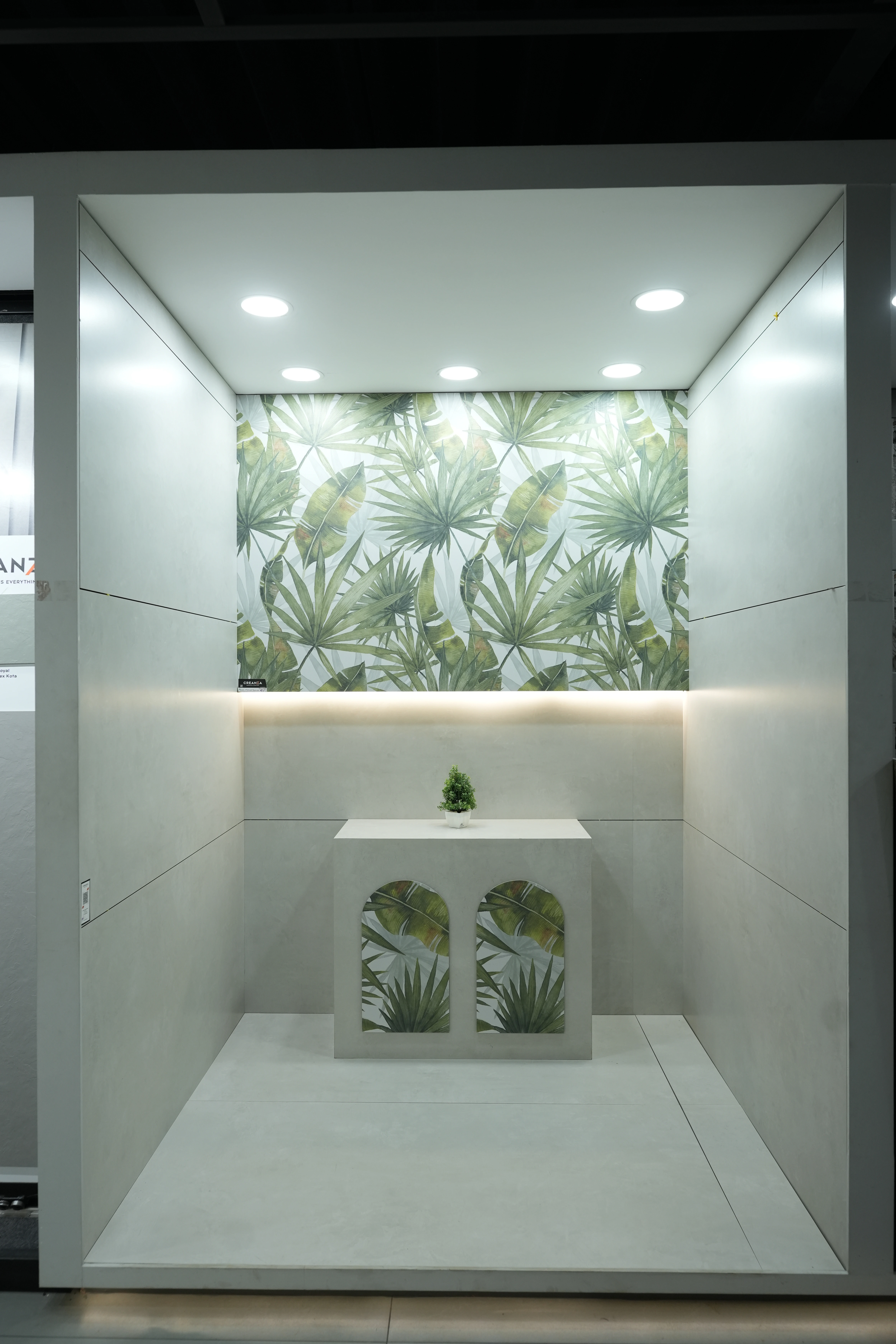 City Ceramics showroom showcasing Creanza tiles with tropical leaf pattern on the wall, featuring a modern minimalist display with ambient lighting.